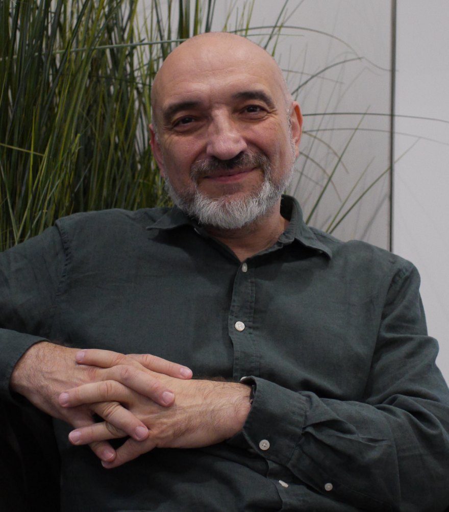 Jan Vodák sedí v křesle s rukama složenýma a usmívá se
